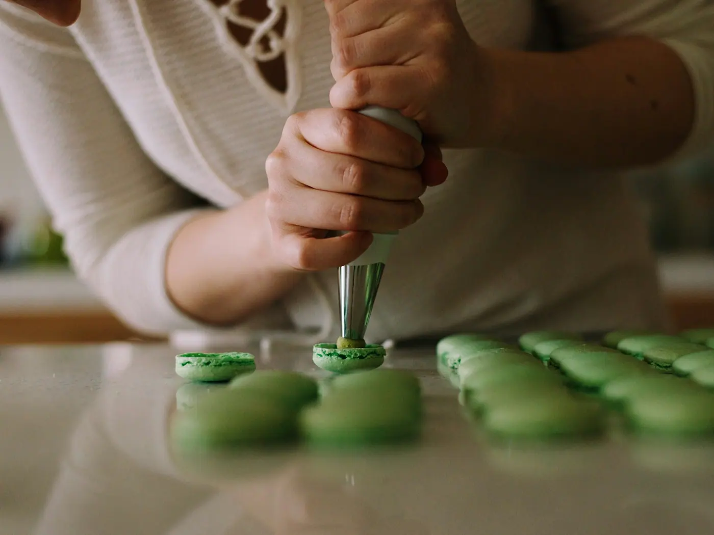 Confeiteira aplicando recheio sobre uma preparação doce
